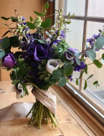 A seasonal floral bouquet with white and purple flowers and eucalyptus leaves as greenery