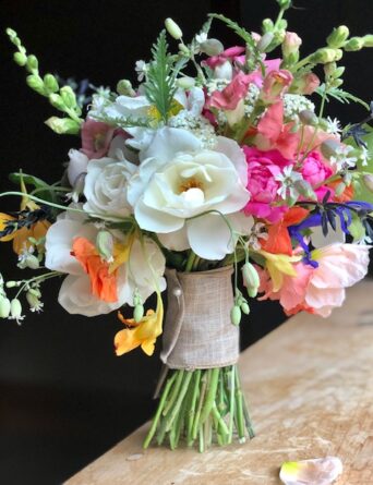 A bouquet with large white flowers surrounded by smaller flowers in varying shades of pink and yellow.